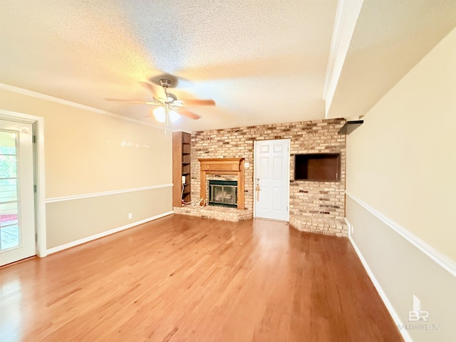 2371 Carriage Dr, Mobile, AL 36693 - unfurnished living room featuring a ceiling fan, a brick fireplace, wood finished floors, a textured ceiling, and ornamental molding