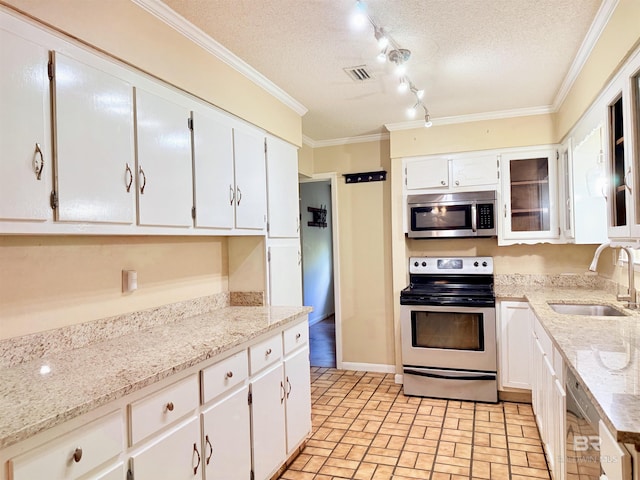 2371 Carriage Dr, Mobile, AL 36693 - kitchen with appliances with stainless steel finishes, white cabinetry, a textured ceiling, brick patterned flooring, and light stone countertops