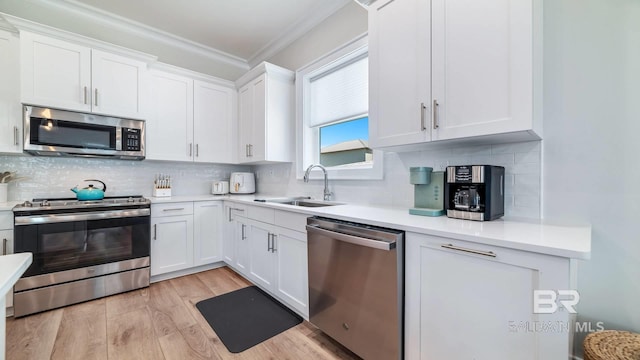 167 E J Cir, Gulf Shores, AL 36542 - kitchen featuring stainless steel appliances, a sink, crown molding, white cabinetry, and light wood finished floors
