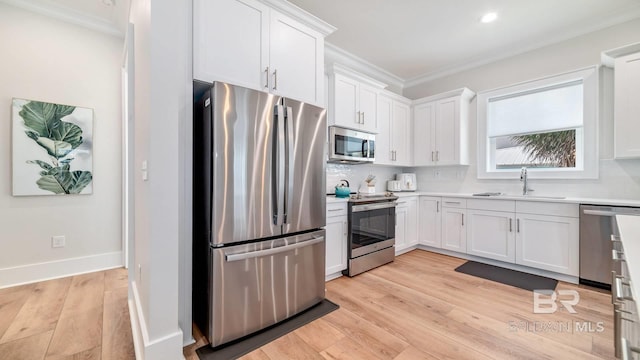 167 E J Cir, Gulf Shores, AL 36542 - kitchen with stainless steel appliances, a sink, crown molding, white cabinets, and light wood-type flooring