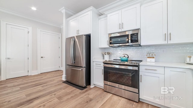 167 E J Cir, Gulf Shores, AL 36542 - kitchen with appliances with stainless steel finishes, ornamental molding, light countertops, light wood-style floors, and white cabinets