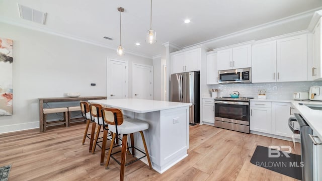 167 E J Cir, Gulf Shores, AL 36542 - kitchen with appliances with stainless steel finishes, crown molding, light wood-type flooring, white cabinetry, and light countertops