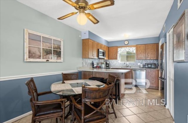 kitchen with sink, light tile patterned floors, appliances with stainless steel finishes, backsplash, and kitchen peninsula