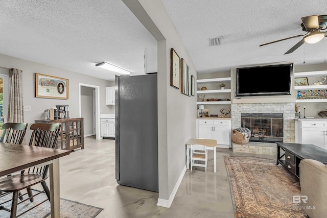 23214 Rochelle Loop, Robertsdale, AL 36567 - living room with ceiling fan, finished concrete flooring, a textured ceiling, and a fireplace