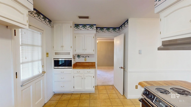 kitchen featuring electric range oven, visible vents, stainless steel microwave, and white cabinetry