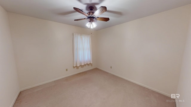 spare room featuring a ceiling fan, light colored carpet, and baseboards