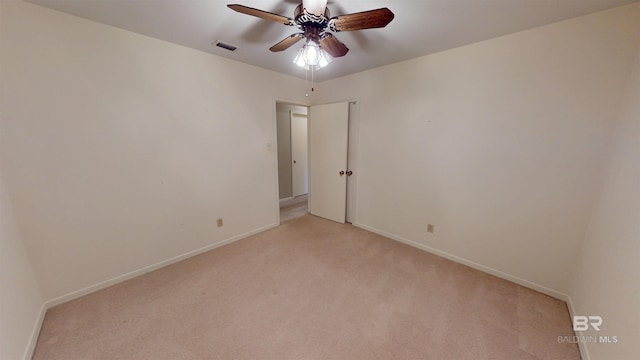 empty room featuring light carpet, ceiling fan, visible vents, and baseboards