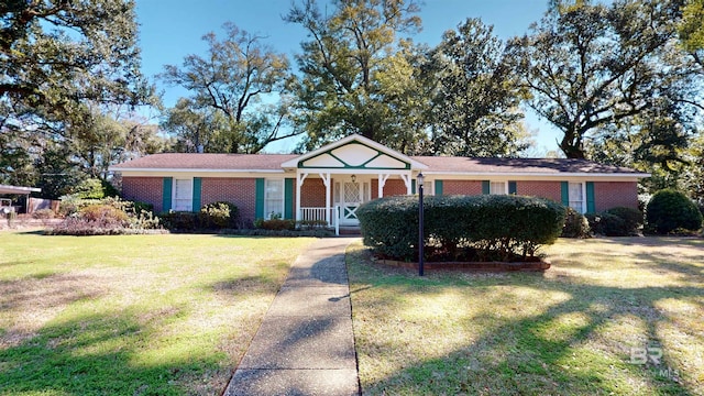 ranch-style home featuring covered porch, brick siding, and a front yard