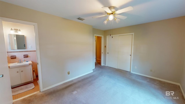 unfurnished bedroom with a closet, visible vents, a sink, ensuite bath, and baseboards