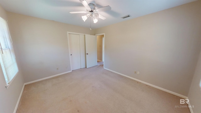 unfurnished bedroom featuring light carpet, a closet, visible vents, and baseboards