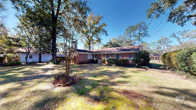 ranch-style home with brick siding, a chimney, and a front yard