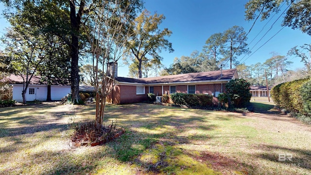 single story home featuring a front lawn, a chimney, and brick siding