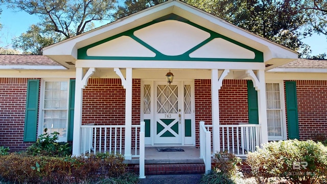 property entrance with a porch and brick siding