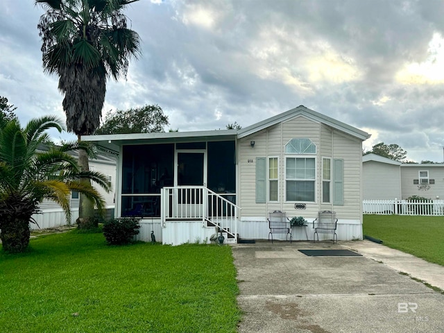 rear view of house with fence, a yard, and a sunroom