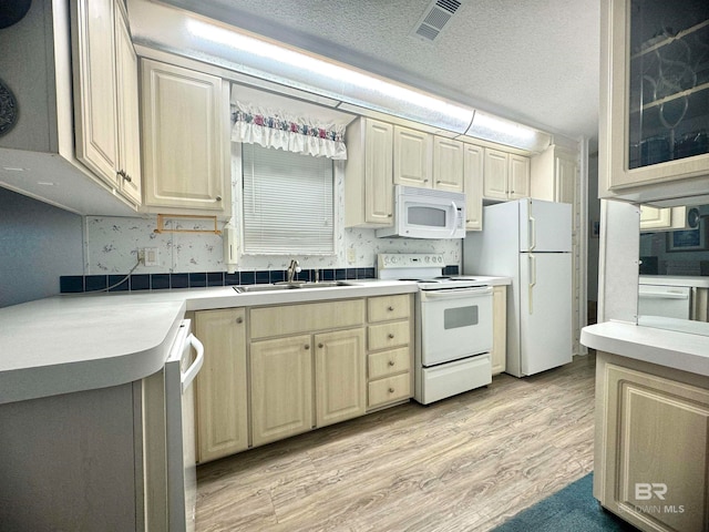 kitchen featuring a sink, white appliances, light countertops, light wood-type flooring, and visible vents