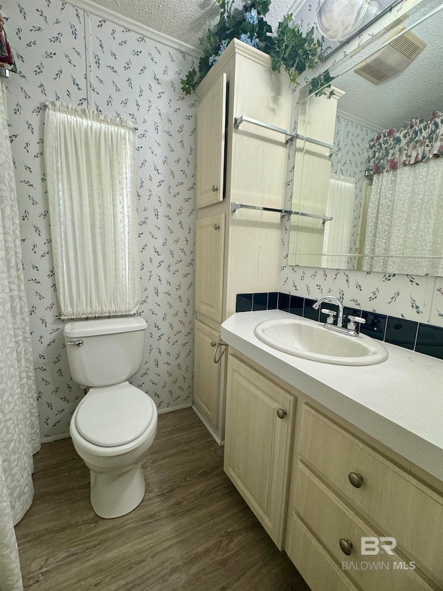 full bathroom with vanity, toilet, wallpapered walls, and wood finished floors