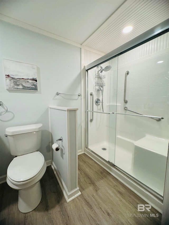 bathroom featuring baseboards, a stall shower, wood finished floors, and toilet