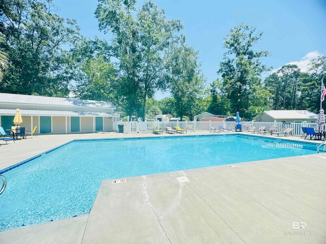 pool with a patio area and fence