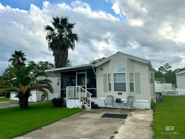 manufactured / mobile home featuring a sunroom, fence, and a front yard