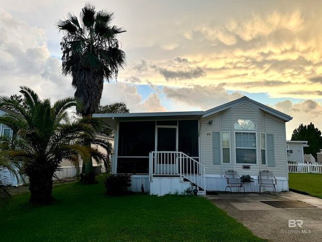 manufactured / mobile home with a front yard, fence, and a sunroom