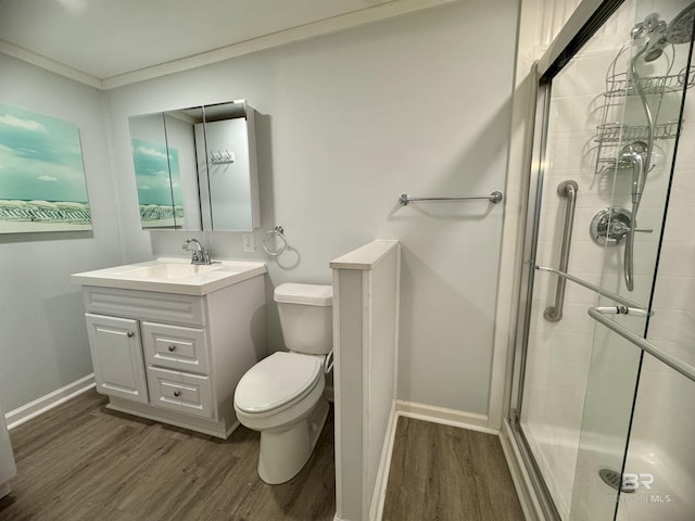 bathroom with toilet, a shower stall, wood finished floors, and vanity