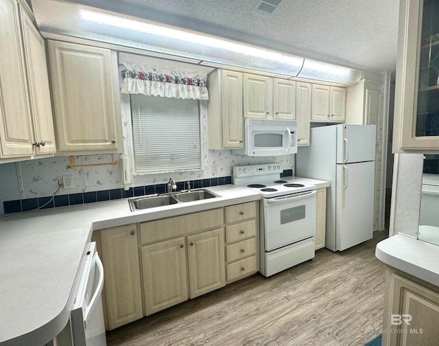 kitchen with a textured ceiling, visible vents, a sink, white appliances, and light wood-style flooring