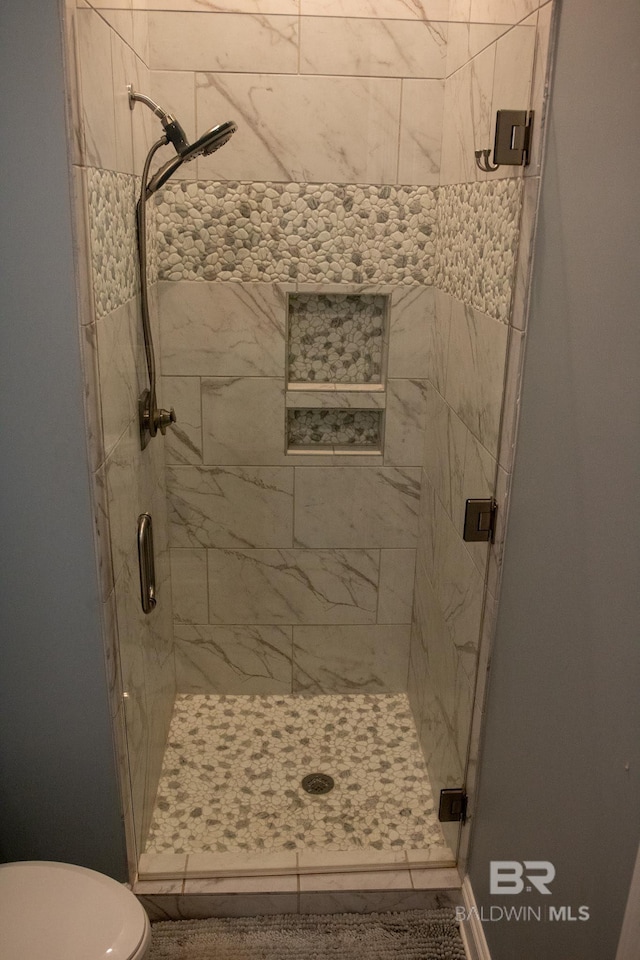 bathroom with a shower with shower door, toilet, and tile patterned floors