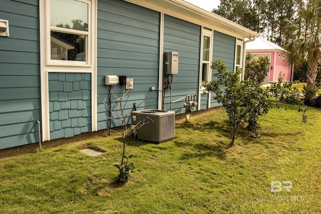 view of side of property with a yard and central air condition unit