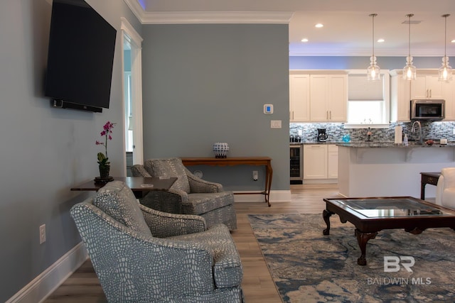 living room with sink, light hardwood / wood-style flooring, crown molding, and wine cooler