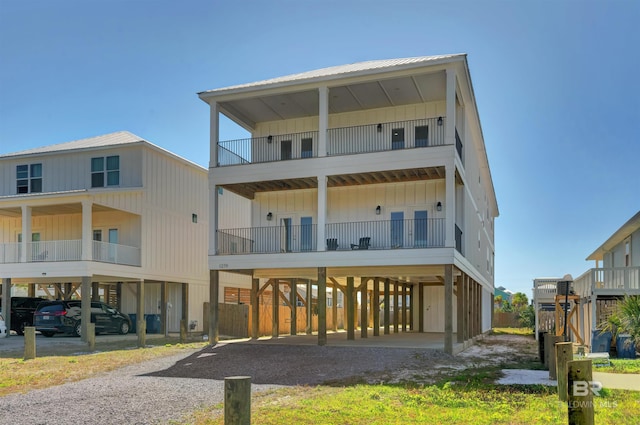 raised beach house with a carport, board and batten siding, and driveway