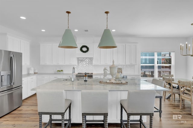 kitchen with white cabinetry, decorative backsplash, wood finished floors, and stainless steel fridge