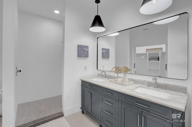 full bathroom featuring double vanity, a shower, baseboards, and a sink