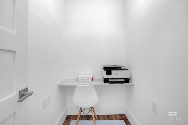 office featuring baseboards, wood finished floors, and built in desk