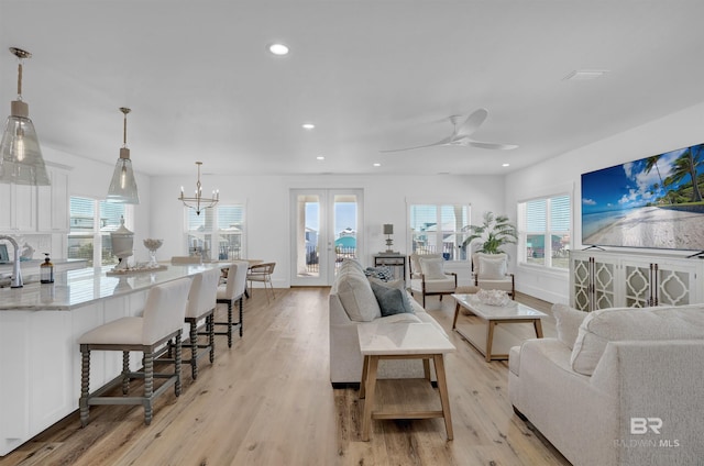 living room featuring baseboards, recessed lighting, french doors, ceiling fan with notable chandelier, and light wood-type flooring