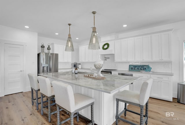 kitchen with backsplash, light wood-type flooring, appliances with stainless steel finishes, white cabinets, and a sink