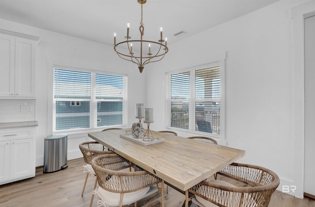 dining area featuring visible vents, a healthy amount of sunlight, light wood-style flooring, and an inviting chandelier