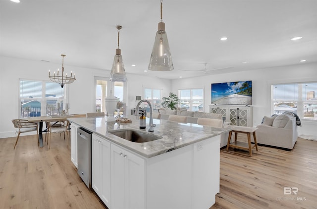 kitchen featuring a center island with sink, open floor plan, light wood finished floors, and a sink