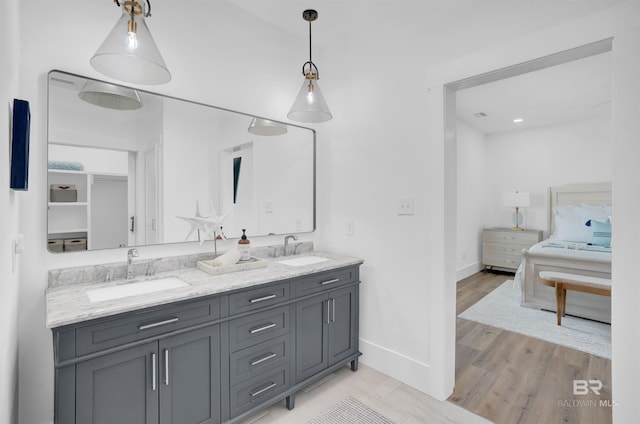 full bath featuring double vanity, wood finished floors, baseboards, and a sink