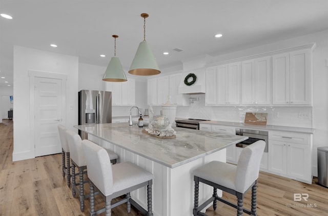 kitchen with white cabinetry, light wood-type flooring, backsplash, and stainless steel appliances