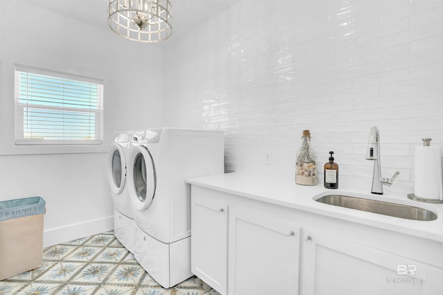 washroom featuring baseboards, washing machine and dryer, an inviting chandelier, cabinet space, and a sink