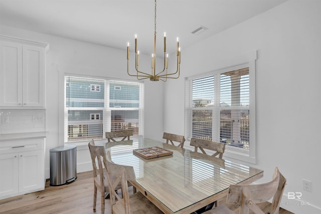 dining space with a notable chandelier, visible vents, and light wood-style floors