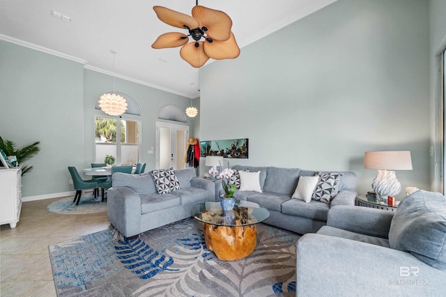 living area with light tile patterned floors, baseboards, ceiling fan, a high ceiling, and crown molding