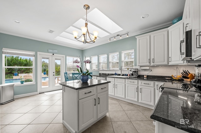 kitchen with tasteful backsplash, a sink, ornamental molding, and light tile patterned floors