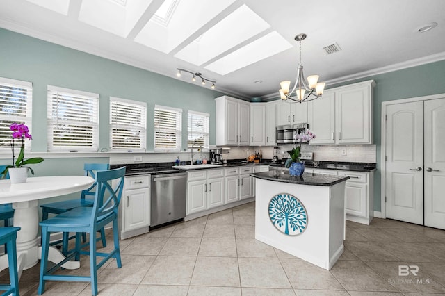 kitchen featuring a skylight, visible vents, dark countertops, appliances with stainless steel finishes, and ornamental molding