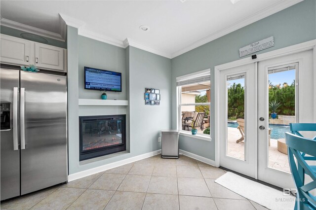 entryway featuring french doors, crown molding, a glass covered fireplace, light tile patterned flooring, and baseboards