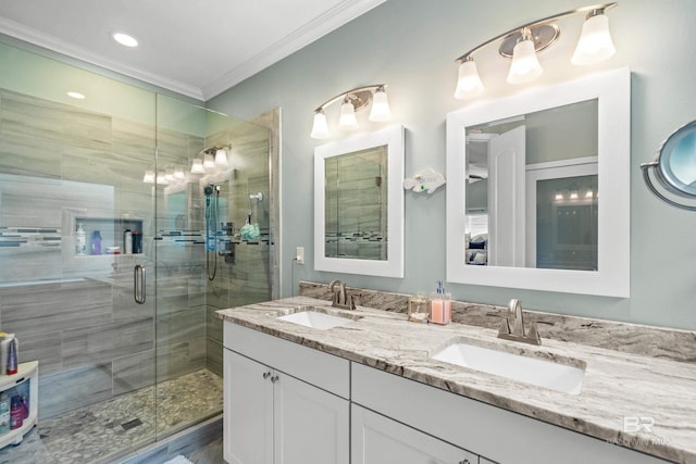 full bathroom featuring double vanity, a stall shower, a sink, and crown molding