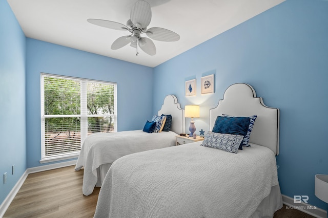 bedroom featuring ceiling fan, baseboards, and wood finished floors