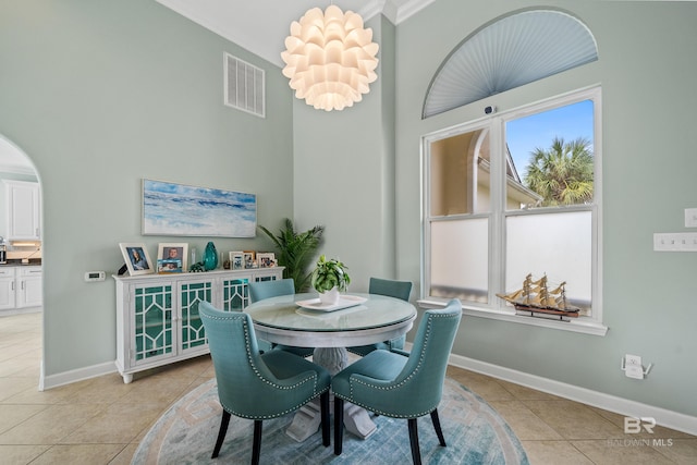 dining area featuring arched walkways, light tile patterned flooring, visible vents, and baseboards