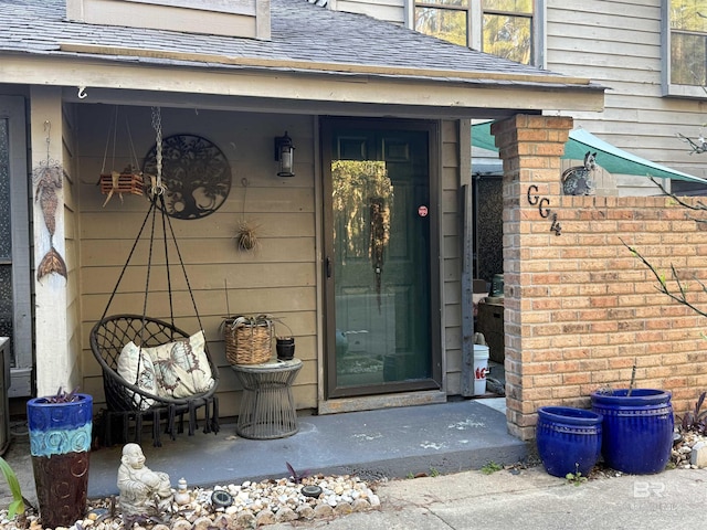 view of exterior entry featuring a shingled roof