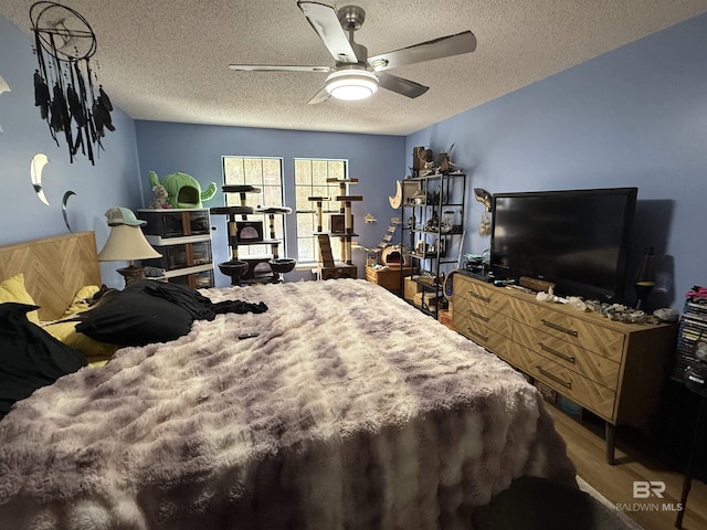 bedroom with ceiling fan, a textured ceiling, and wood finished floors